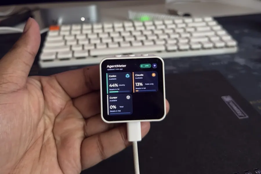 AgentMeter on a desk showing live Codex, Claude, and Cursor usage on its AMOLED screen